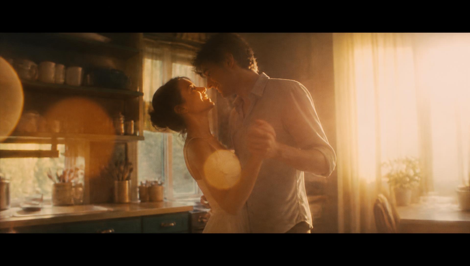 A young couple dancing in a sunlit kitchen, remembered in golden light